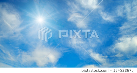 Bright sun shining in a clear blue sky with white clouds. Bright sun shining in a clear blue sky with white clouds. 134528673