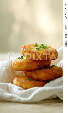 Stack of golden potato pancakes garnished with fresh dill on a soft linen napkin Stack of golden potato pancakes garnished with fresh dill on a soft linen napkin 134529306