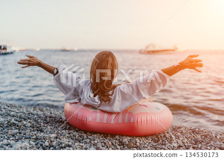 Woman, beach, sunset. Relaxed woman on pebble beach enjoying the ocean view at sunset. Woman, beach, sunset. Relaxed woman on pebble beach enjoying the ocean view at sunset. 134530173