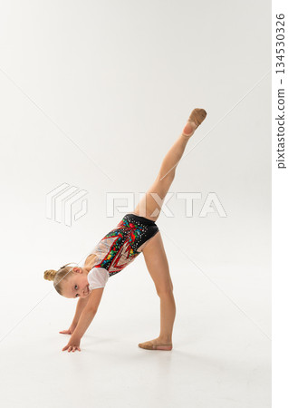 Gymnast girl with cochlear implant doing split pose on hands. Empowerment, flexibility, and hearing inclusion through movement and artistic expression. 134530326