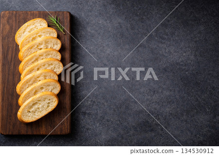 法國麵包整齊地擺放在一塊帶有木質邊框的深色石板上。 134530912