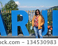 Young beautiful Indian woman posing in front of blue Darjeeling sign board at a scenic hill station viewpoint in West Bengal India 134530983