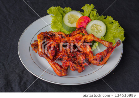 Ayam Taliwang Traditional Grilled Spicy Chicken from Lombok Indonesia served with fresh vegetable garnish. Ayam Taliwang Traditional Grilled Spicy Chicken from Lombok Indonesia served with fresh vegetable garnish. 134530999