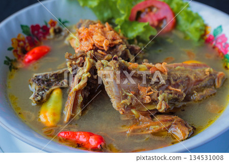 Spicy rich Indonesian beef soup served in a traditional patterned bowl with fresh chili and fried shallots. Spicy rich Indonesian beef soup served in a traditional patterned bowl with fresh chili and fried shallots. 134531008