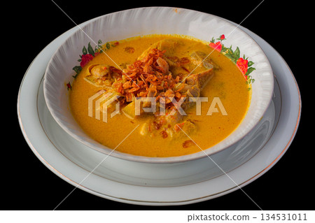 Traditional Indonesian Yellow Curry or Gulai Daging from Lombok served in a bowl with fried shallots on black background. Traditional Indonesian Yellow Curry or Gulai Daging from Lombok served in a bowl with fried shallots on black background. 134531011