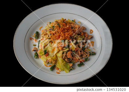 Plecing Sayur Lombok, traditional Indonesian spicy vegetable salad with shredded chicken and fried shallots on white plate isolated on black background. Plecing Sayur Lombok, traditional Indonesian spicy vegetable salad with shredded chicken and fried shallots on white plate isolated on black background. 134531020