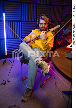 Man vocal artist singing in a recording studio with guitar. Male singer singing a song and playing guitar. Sound record and music streaming concept 134531622