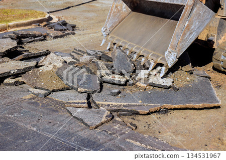 Construction crew uses loader to remove damaged asphalt from city street to prepare for repairs. 134531967