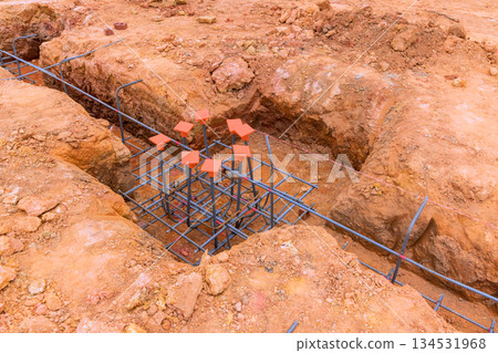 Workers prepare rebar structure in ground for upcoming concrete pour at construction site. Workers prepare rebar structure in ground for upcoming concrete pour at construction site. 134531968