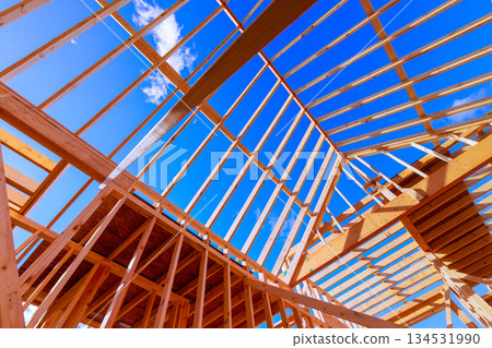 Workers are constructing wooden frame beams for new building under roof trusses Workers are constructing wooden frame beams for new building under roof trusses 134531990