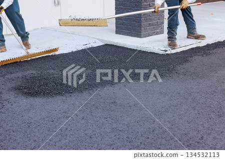 Construction workers spread hot asphalt on pavement near building road maintenance. Construction workers spread hot asphalt on pavement near building road maintenance. 134532113