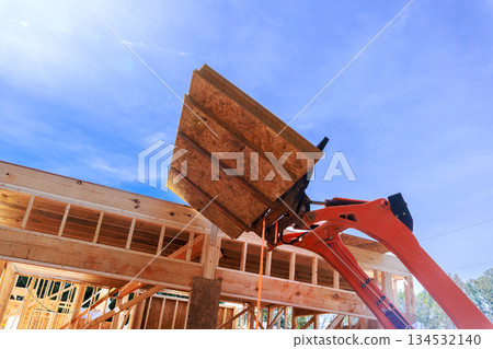 Heavy machinery lifts wooden osb panels for construction under assembly new home 134532140
