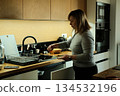 Woman stands in kitchen peeling carrot over sink. Zero waste lifestyle, organic waste, composting at home, sustainable living. 134532196