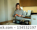 Woman peels carrot at wooden kitchen counter in modern apartment. Whole foods, organic vegetables, conscious eating. 134532197