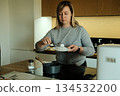 Woman serves cooked rice from pot onto plate in modern kitchen. Meal preparation, batch cooking, healthy eating habits, home wellness. 134532200