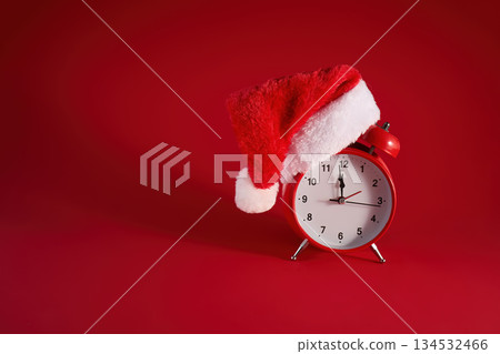 Festive Time. A red clock adorned with a Santa hat against a vibrant red background. 134532466