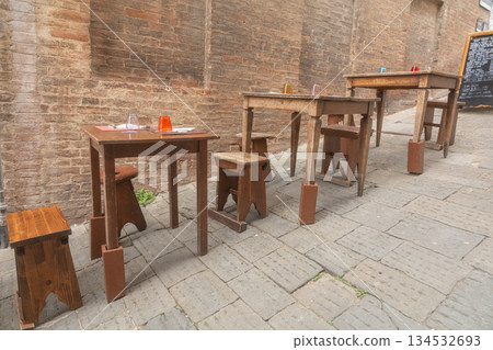 Empty restaurant tables in old town street. Calm European dining scene Empty restaurant tables in old town street. Calm European dining scene 134532693