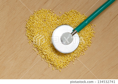 Millet groats heart shaped on wooden surface. 134532741