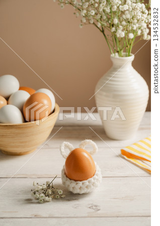 Easter eggs background. White eggs in wooden bowl and gypsophila flowers in a vase. Spring holiday Easter eggs background. White eggs in wooden bowl and gypsophila flowers in a vase. Spring holiday 134532832