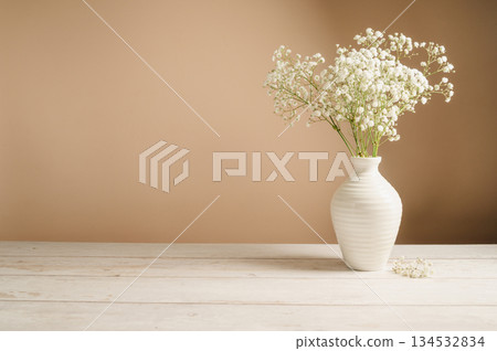 White floral background. Soft home decor, vase with white small flowers on white background, copy space 134532834