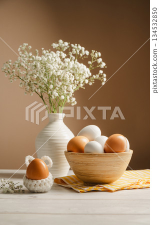 Easter eggs background. White eggs in wooden bowl and gypsophila flowers in a vase. Spring holiday Easter eggs background. White eggs in wooden bowl and gypsophila flowers in a vase. Spring holiday 134532850