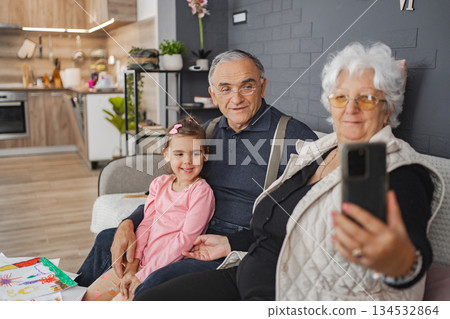 Grandparents and granddaughter smile in living room Grandparents and granddaughter smile in living room 134532864