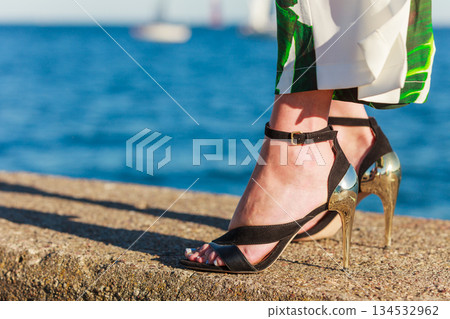 Woman feet in high heels shoes on sea pier Woman feet in high heels shoes on sea pier 134532962