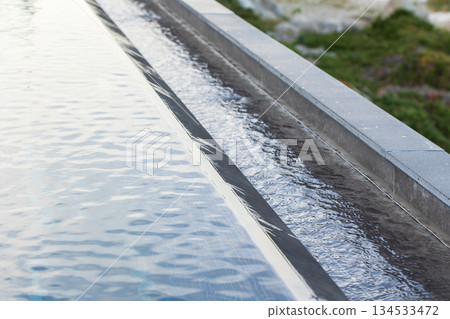 A clean, linear pool edge features a calm, reflective water surface 134533472
