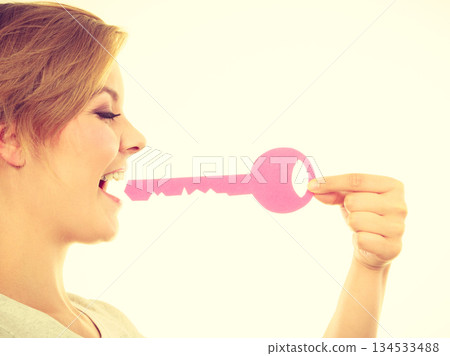 Blonde teenage girl biting pink key Blonde teenage girl biting pink key 134533488