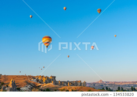 Hot air balloon flying over rocky landscape at sunrise in Cappadocia. Turkey 134533820