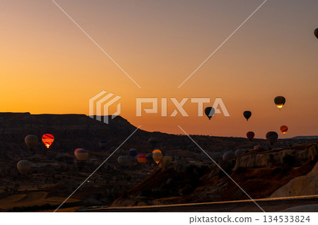 Hot air balloon flying over rocky landscape at sunrise in Cappadocia. Turkey 134533824
