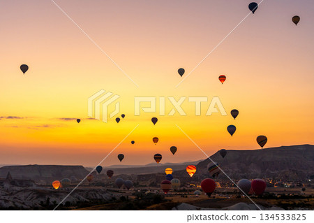 Hot air balloon flying over rocky landscape at sunrise in Cappadocia. Turkey 134533825