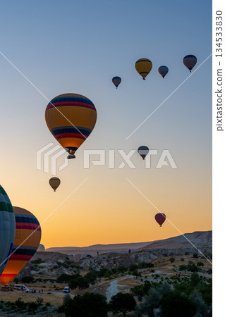 Hot air balloon flying over rocky landscape at sunrise in Cappadocia. Turkey Hot air balloon flying over rocky landscape at sunrise in Cappadocia. Turkey 134533830