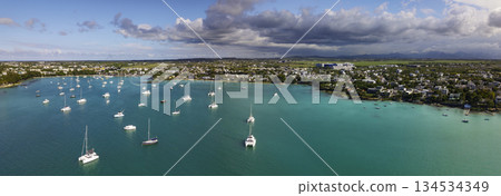 Aerial panorama of Grand Baie Mauritius with turquoise lagoon anchored catamarans and town coastline under dramatic clouds Aerial panorama of Grand Baie Mauritius with turquoise lagoon anchored catamarans and town coastline under dramatic clouds 134534349