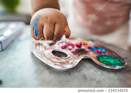 Young artist exploring colors with paint on a palette Young artist exploring colors with paint on a palette 134534870