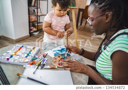 Creative mother and child enjoy painting together at home 134534872