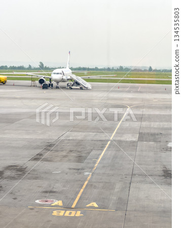 Regional jet preparing for boarding on cloudy apron 134535803