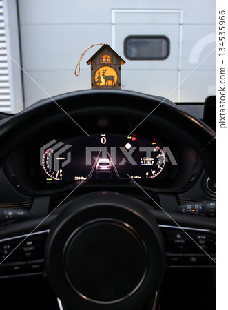 A hanging Christmas themed toy house sits on the visor above the car's dashboard A hanging Christmas themed toy house sits on the visor above the car's dashboard 134535966
