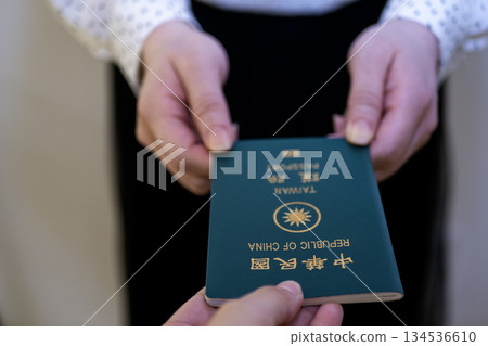 A woman's hand handing over a Taiwanese passport A woman's hand handing over a Taiwanese passport 134536610