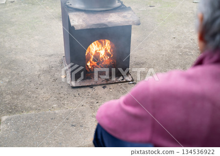 Elderly man warming himself by a wood-burning stove Elderly man warming himself by a wood-burning stove 134536922