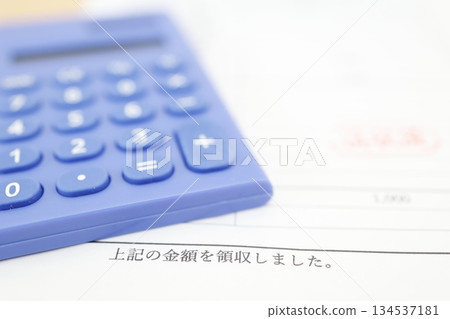 Image of a receipt and a blue calculator with the amount collected. Image of a receipt and a blue calculator with the amount collected. 134537181