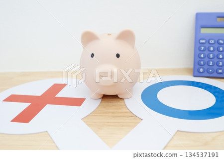 A piggy bank and a plate showing the good and bad aspects of saving. 134537191