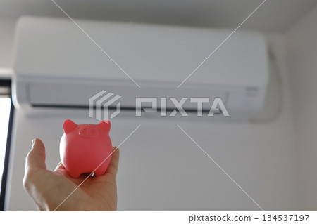 An image of saving energy and reducing electricity bills using an air conditioner and a piggy bank. 134537197