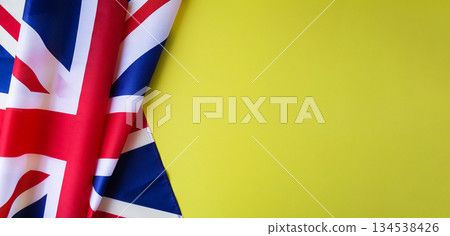 National symbol of Great Britain patriotic symbol on yellow background with place for text. British full framed wave UK fabric flag. Copy space. Concept of Independence National symbol of Great Britain patriotic symbol on yellow background with place for text. British full framed wave UK fabric flag. Copy space. Concept of Independence 134538426