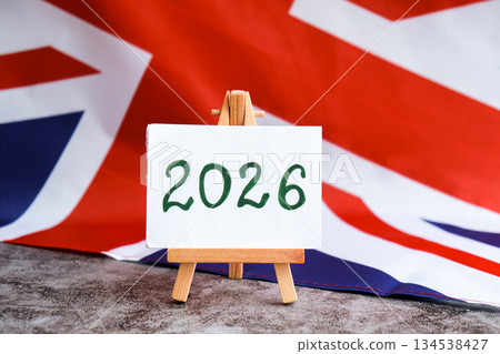 Paper note with text 2026 on National symbol of Great Britain. British wave the UK silky flag background. Financial outlook planning, new year annual report Paper note with text 2026 on National symbol of Great Britain. British wave the UK silky flag background. Financial outlook planning, new year annual report 134538427