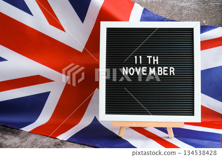 Minimal patriotic scene with signboard and waving flag date 11th November UNITED KINGDOM with national colors Festive background with British flag and message board with text Great Britain Minimal patriotic scene with signboard and waving flag date 11th November UNITED KINGDOM with national colors Festive background with British flag and message board with text Great Britain 134538428