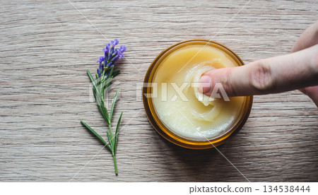 Mixing organic lavender balm with fingertips on a wooden table Mixing organic lavender balm with fingertips on a wooden table 134538444