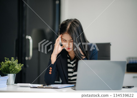 Asian business woman is stressed, bored, and overthinking from working on a tablet Asian business woman is stressed, bored, and overthinking from working on a tablet 134539622