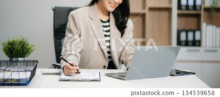 Beautiful Asian businesswoman typing laptop and tablet Placed at the table at the office 134539658