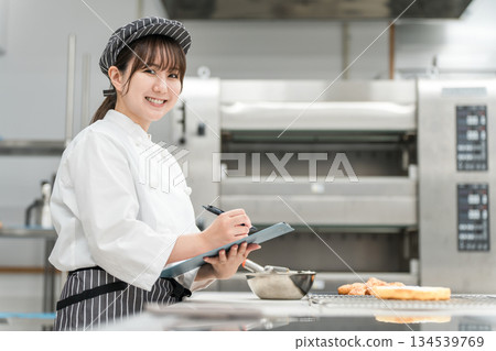 Female staff members in the kitchen check bread products, conduct research, develop products, manage hygiene, and control quality. 134539769
